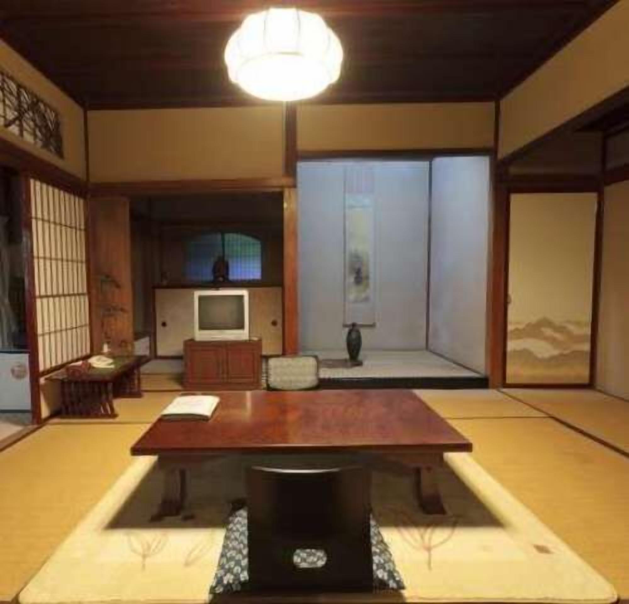 Una estança japonesa tradicional amb sòl de tatami, una taula baixa, una televisió i portes corredisses.