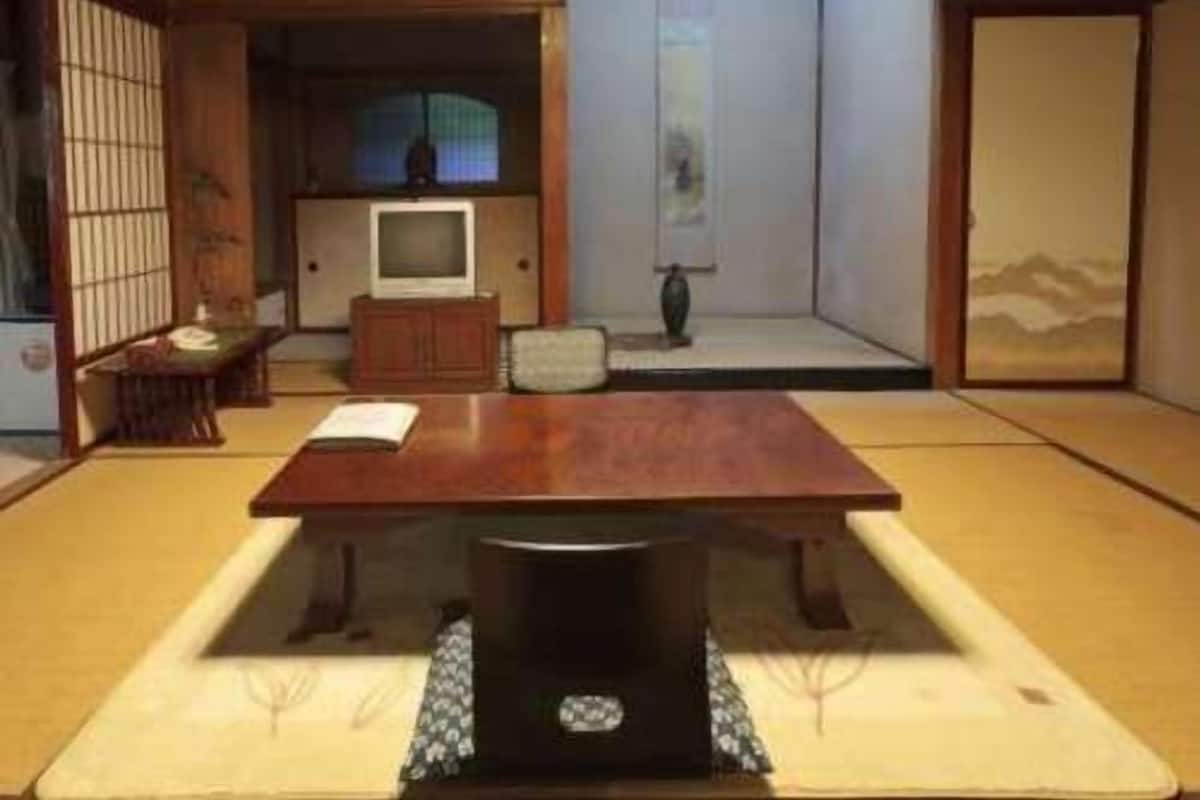 Una estança japonesa tradicional amb sòl de tatami, una taula baixa, una televisió i portes corredisses.
