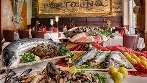 Ein Meeresfrüchtebuffet mit verschiedenen Fischen und Schalentieren, eine Ziegelwand mit der Aufschrift 'PORTOFINO' und eine Statue.
