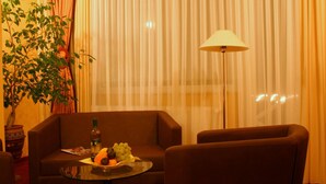 Ein Zimmer mit einer Couch, einem Tisch mit Obst, einer Lampe und einer Pflanze.
