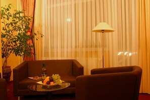 Une pièce avec un canapé, une table sur laquelle se trouvent des fruits, une lampe et une plante.