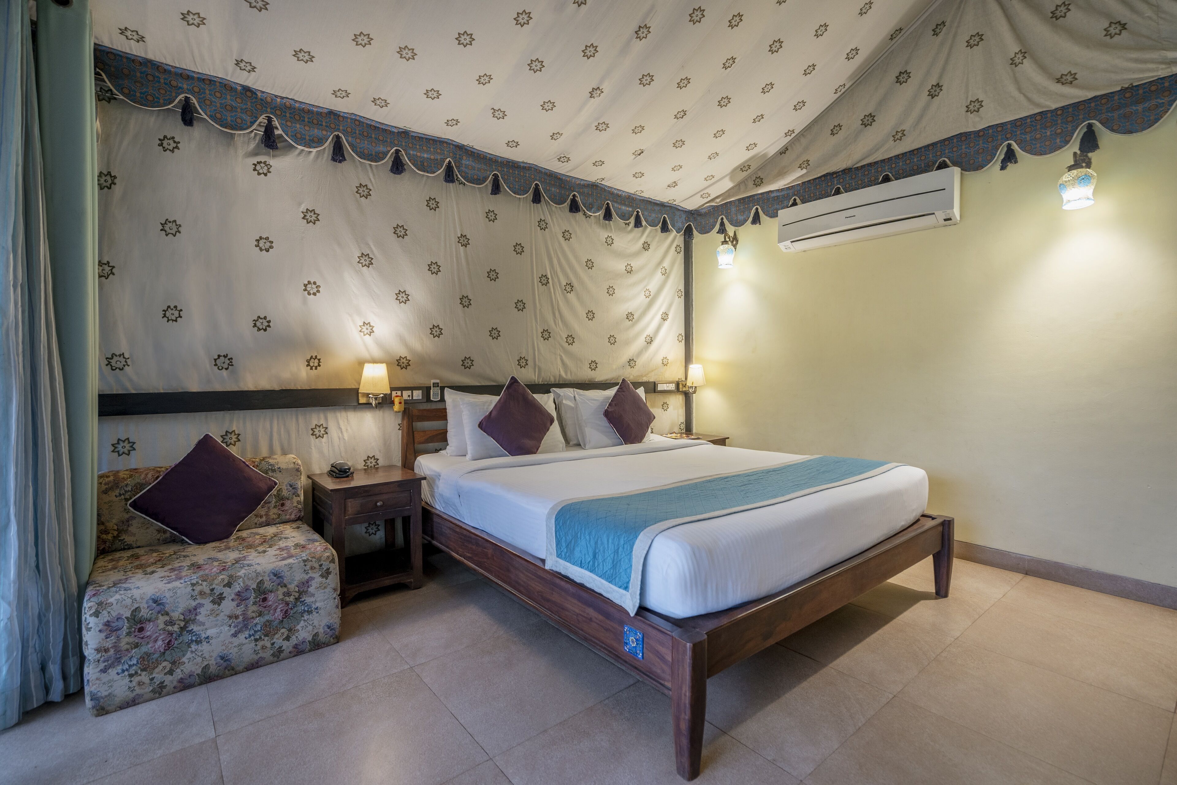 Een slaapkamer met een bed, nachtkastjes, een stoel en een airconditioning.