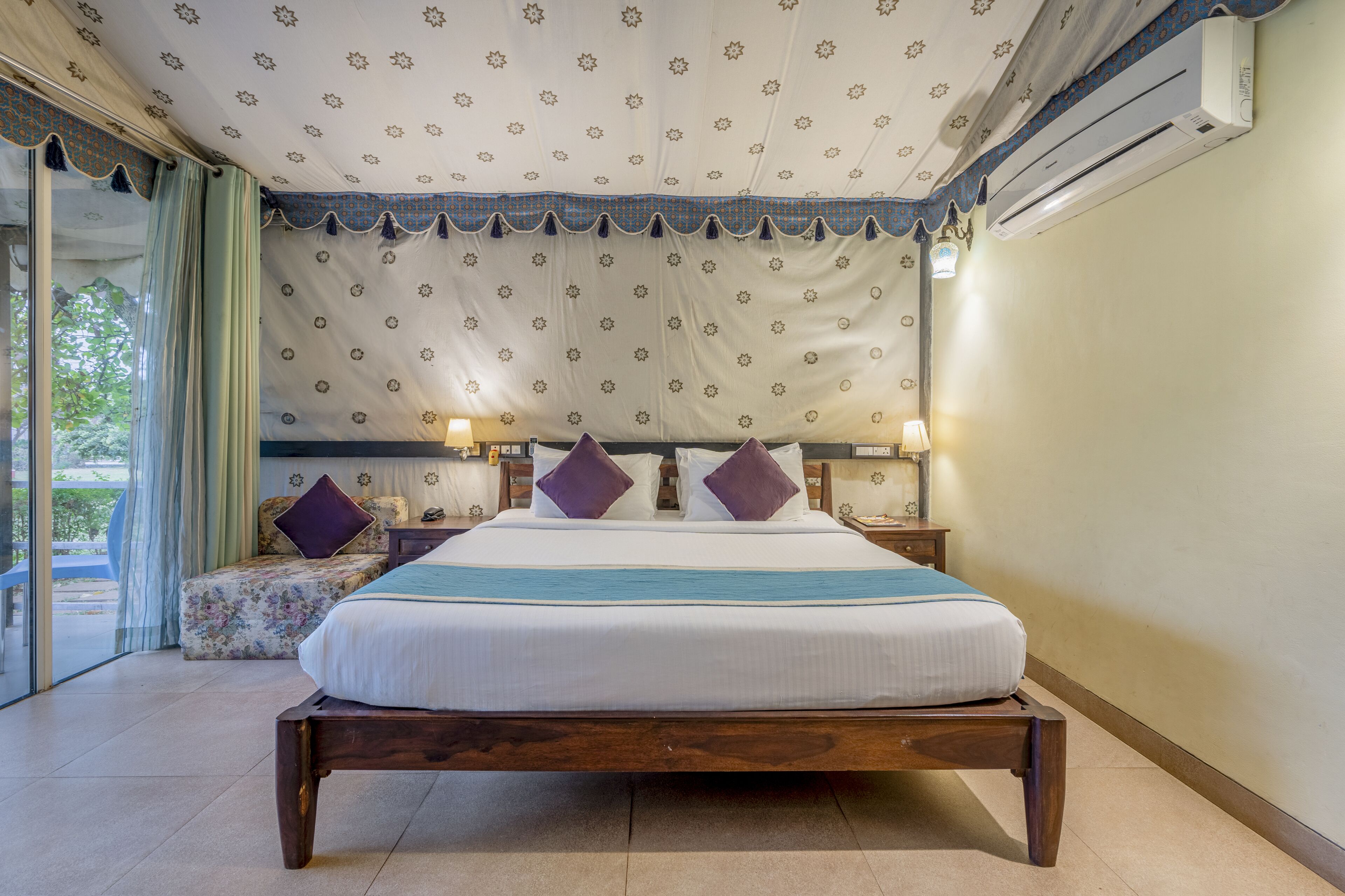 A bedroom with a large bed, two bedside tables, a nightstand, and a window with curtains.