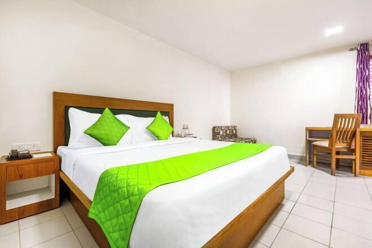 Una habitación de hotel con una cama, una mesita de noche, una silla y una pequeña mesa.