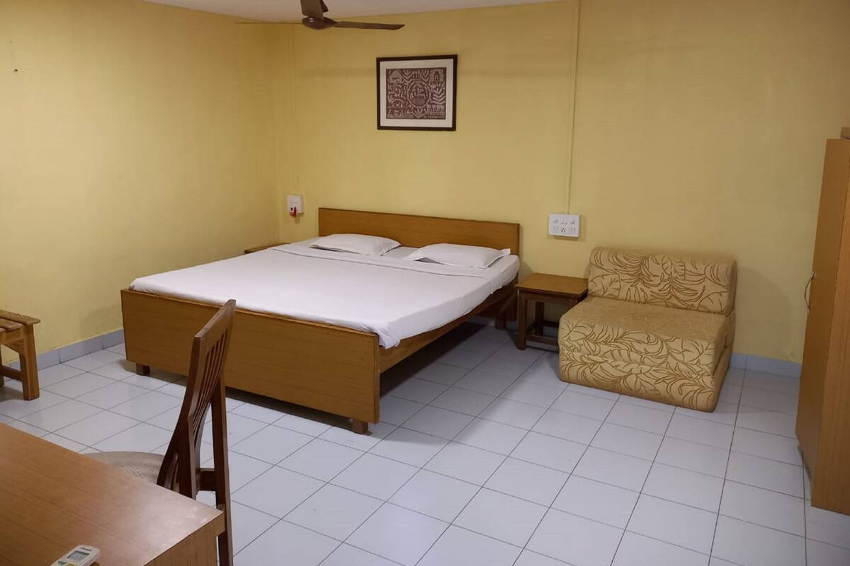 Una habitación con una cama de madera, una silla, una mesa y un ventilador de techo.