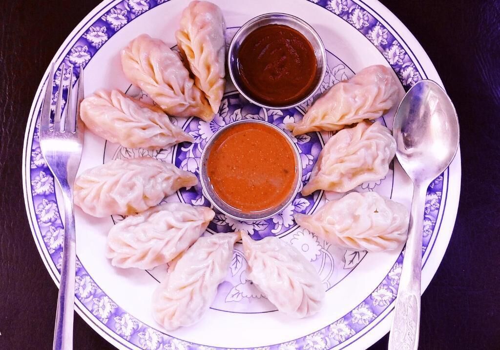 A plate of dumplings with two dipping sauces.