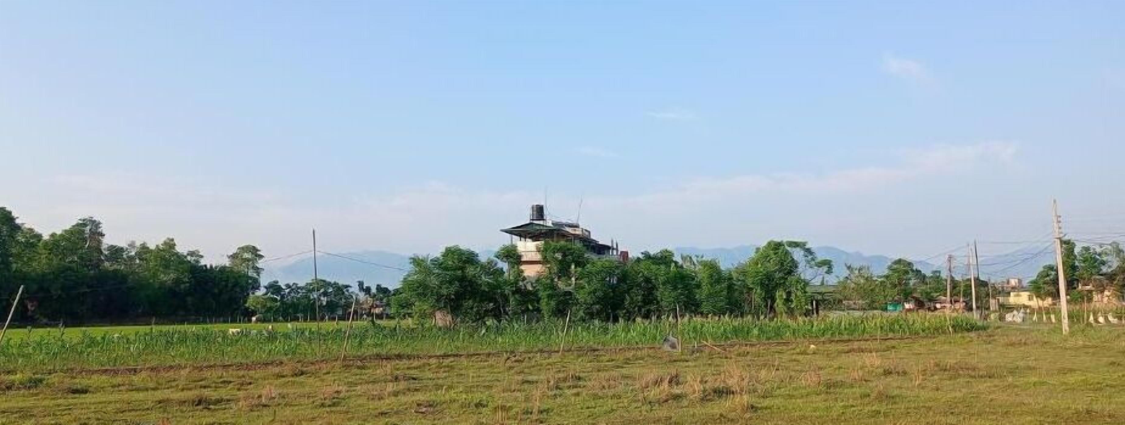 Un paisaje rural con un edificio solitario en el centro, rodeado de campos y árboles.