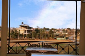 A view from a balcony with a table and chairs, overlooking a residential area with houses and trees. - Hotel National Park (Sauraha)