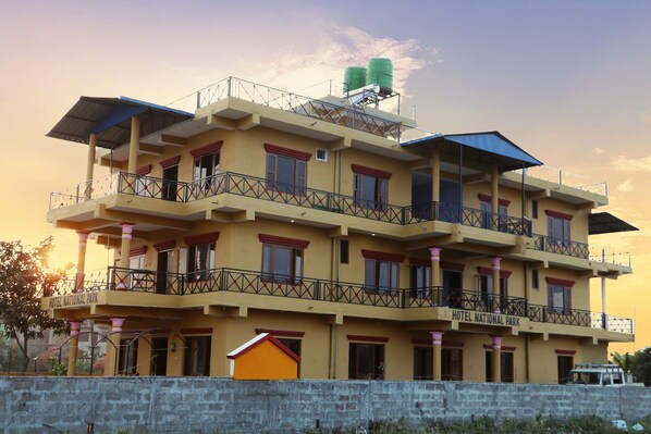 A multi-story hotel with balconies, a water tank on the roof, and a sign indicating it is a national park hotel.