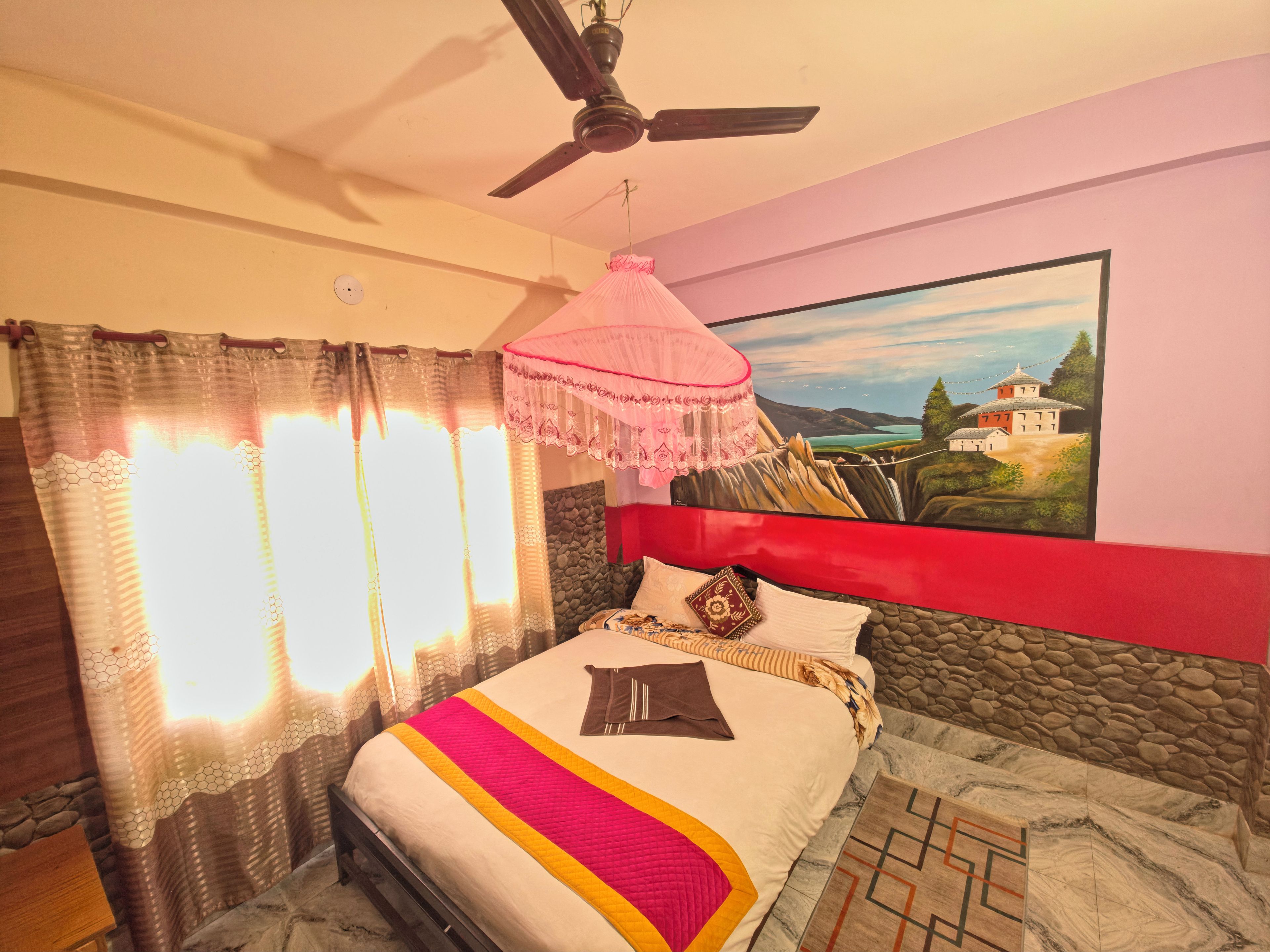 Un dormitorio con una cama, un ventilador de techo, un cuadro en la pared y una ventana con cortinas.