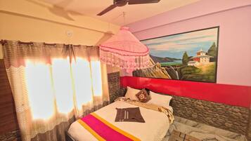Un dormitorio con una cama, un ventilador de techo, un cuadro en la pared y una ventana con cortinas.
