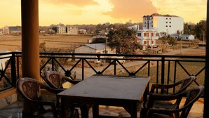 Una terraza con mesa y sillas, con vistas a un paisaje rural con edificios y campos.