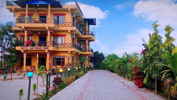 Un hotel de varios pisos con balcones, un letrero que dice "HOTEL NATIONAL PARK" y un camino pavimentado que conduce a la entrada.