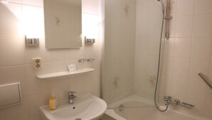 Een badkamer met een wastafel, spiegel en douche.