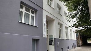 Een modern gebouw met een grijze gevel, een witte deur en een bordje dat aangeeft dat het een 'CH' hotel is.
