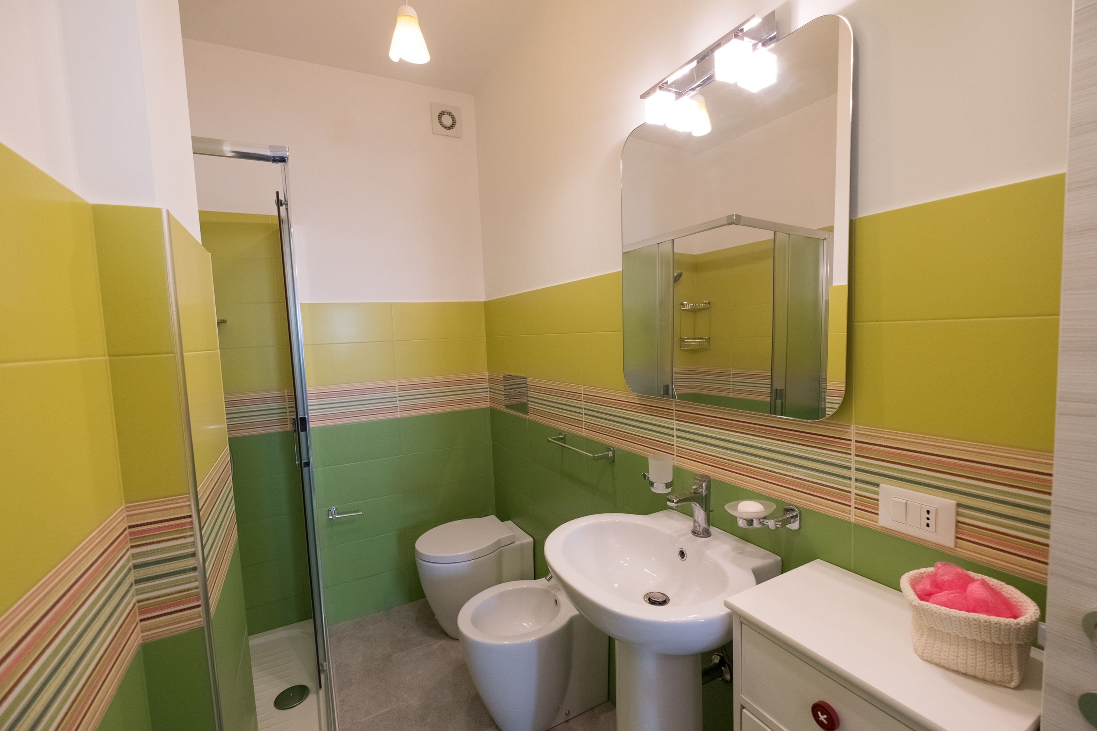 Une salle de bain équipée d’une douche, de toilettes, d’un lavabo et d’un miroir.