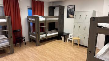 A dormitory room with bunk beds, a desk, a chair, and a set of lockers.
