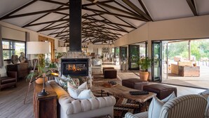 A spacious living room with a fireplace, comfortable seating, and large windows offering a view of the outdoors.