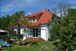 A two-story house with a red-tiled roof, a front porch with steps, and a small garden area with a bench and a bicycle. - Altes Haus der Seefahrtschule Grünbaum Ostseebad-Wustrow (near Ahrenshoop) Darss (Ostseebad-Wustrow)