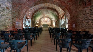 A church interior with a brick archway leading to an altar, rows of pews, and a stone floor. - Cascina Veja (Chiusa di Pesio)
