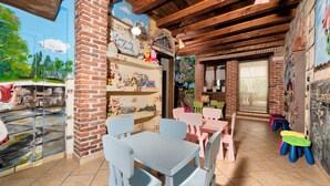 A children's playroom with brick walls, wooden beams, and colorful furniture. - Cascina Veja (Chiusa di Pesio)