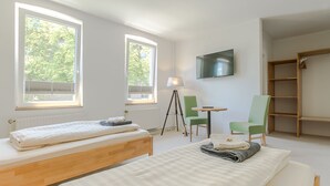 Una habitación con dos camas, televisión, una silla y una mesita.