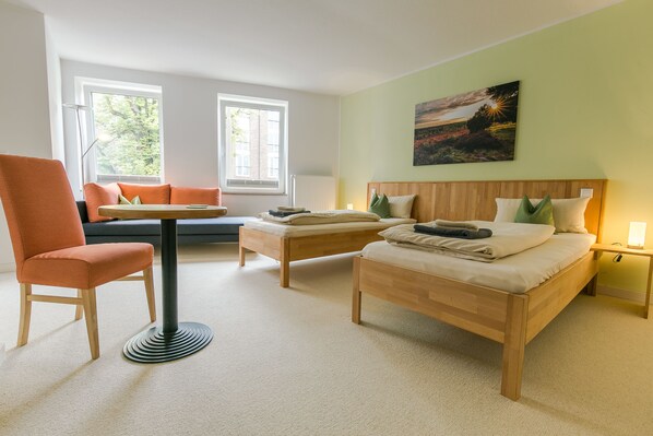 Una habitación con dos camas de madera, un sofá, una mesa y una silla.