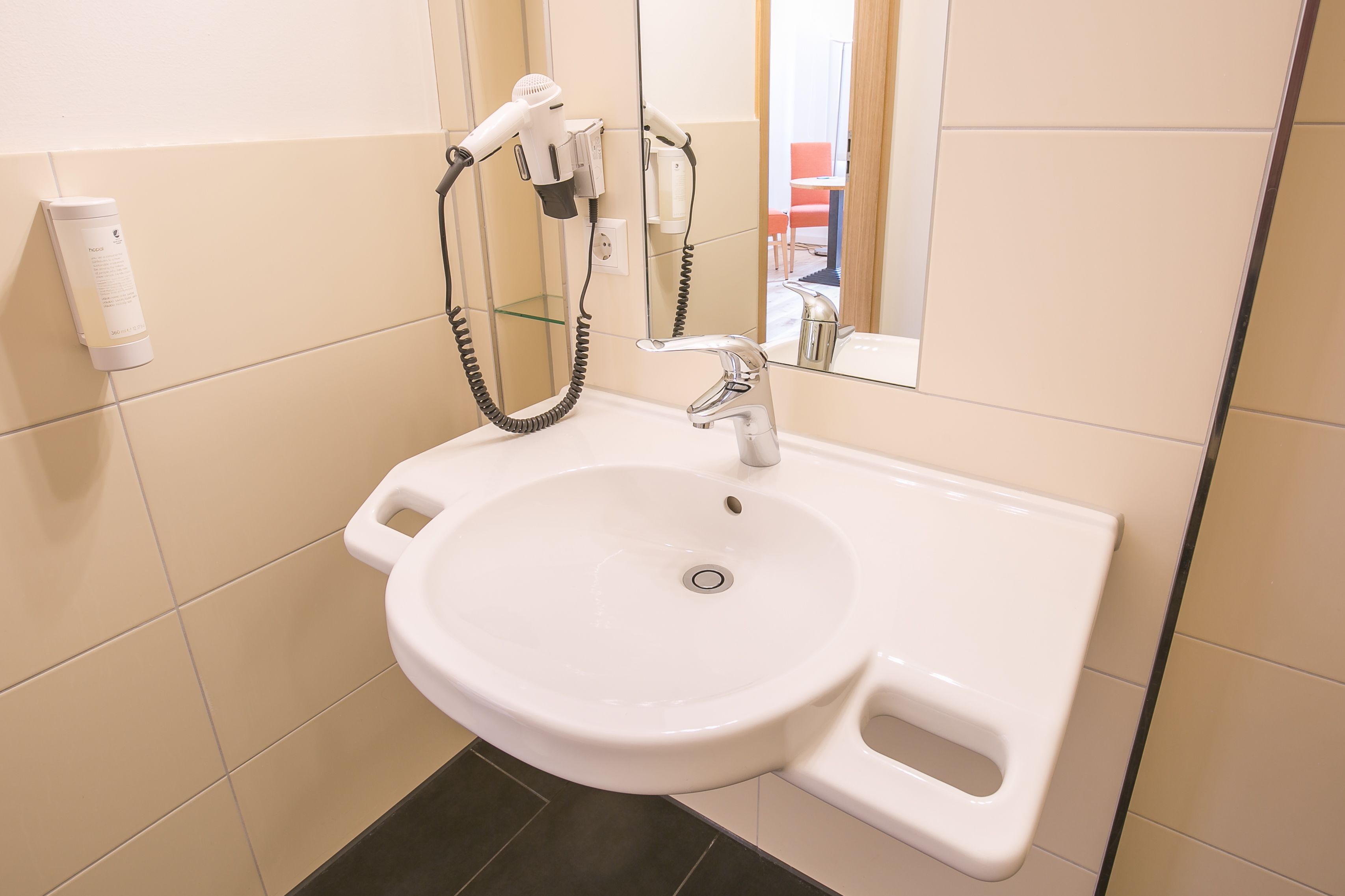 Un baño con un lavabo blanco, un secador de pelo y un espejo.