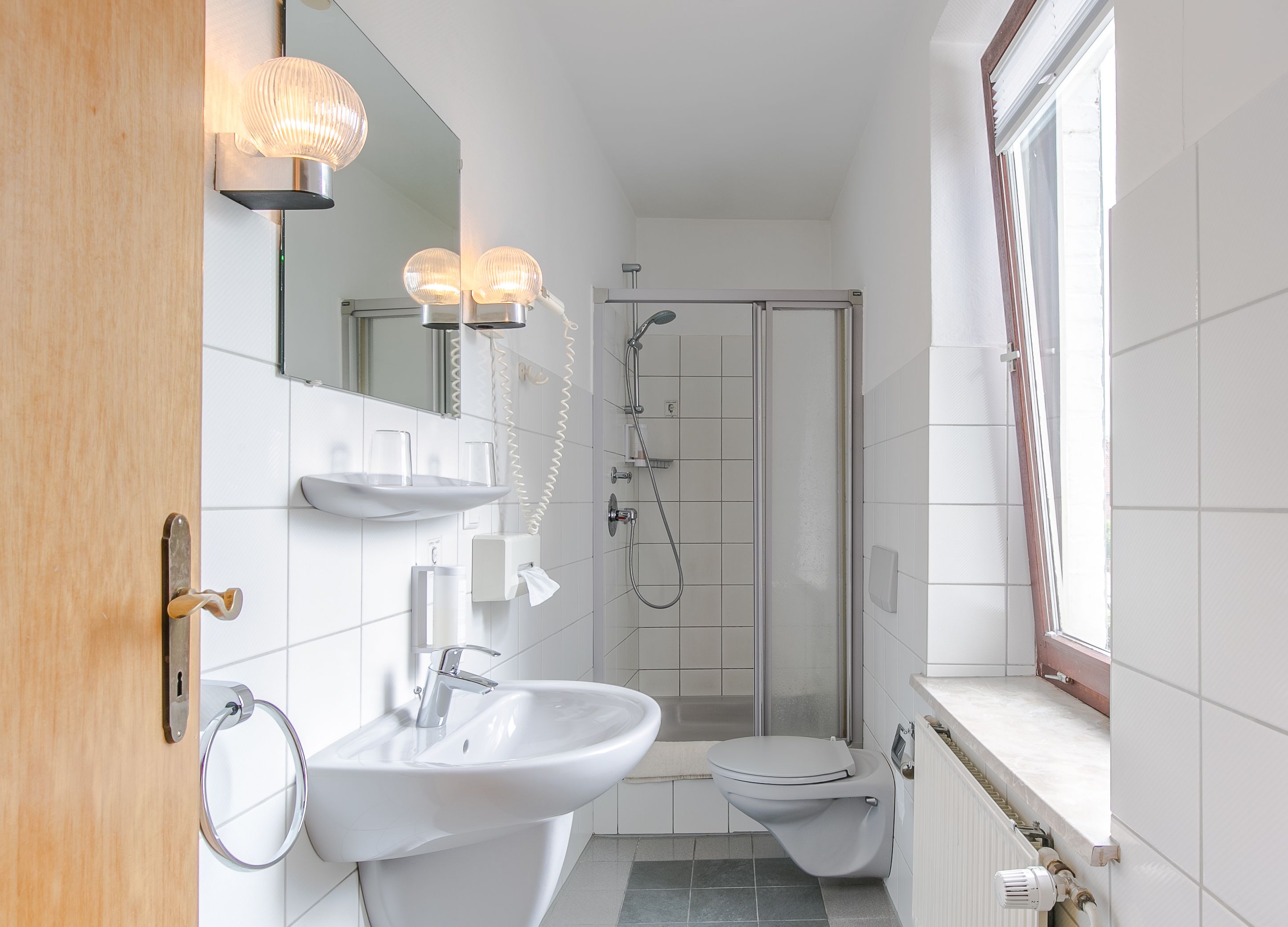 Un baño moderno con lavamanos, inodoro y ducha.