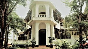 A two-story building with a balcony, surrounded by trees and potted plants. - PJ Lodge (Dar es Salaam)