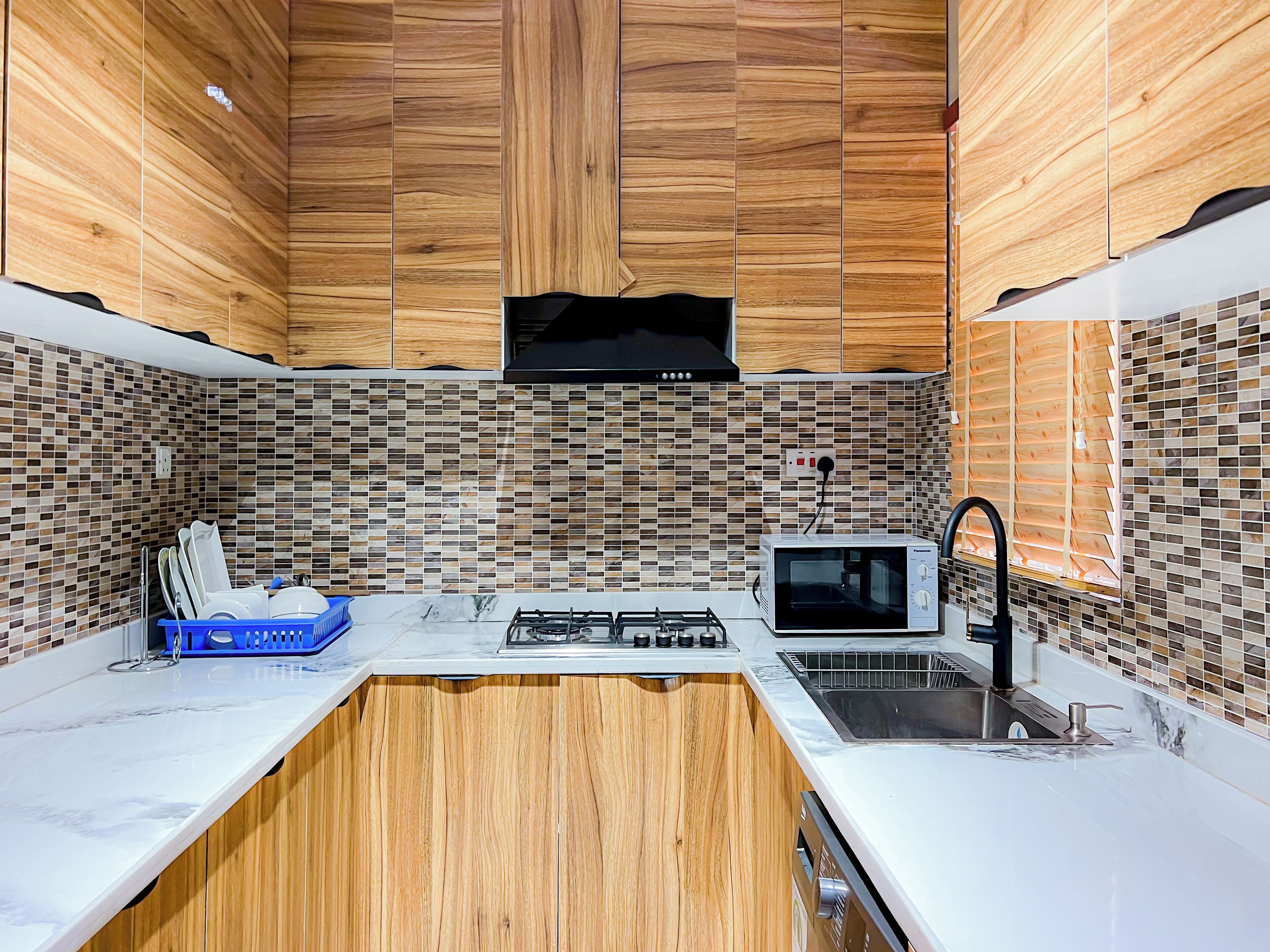 A modern kitchen with wooden cabinets, a gas stove, a microwave, and a sink.