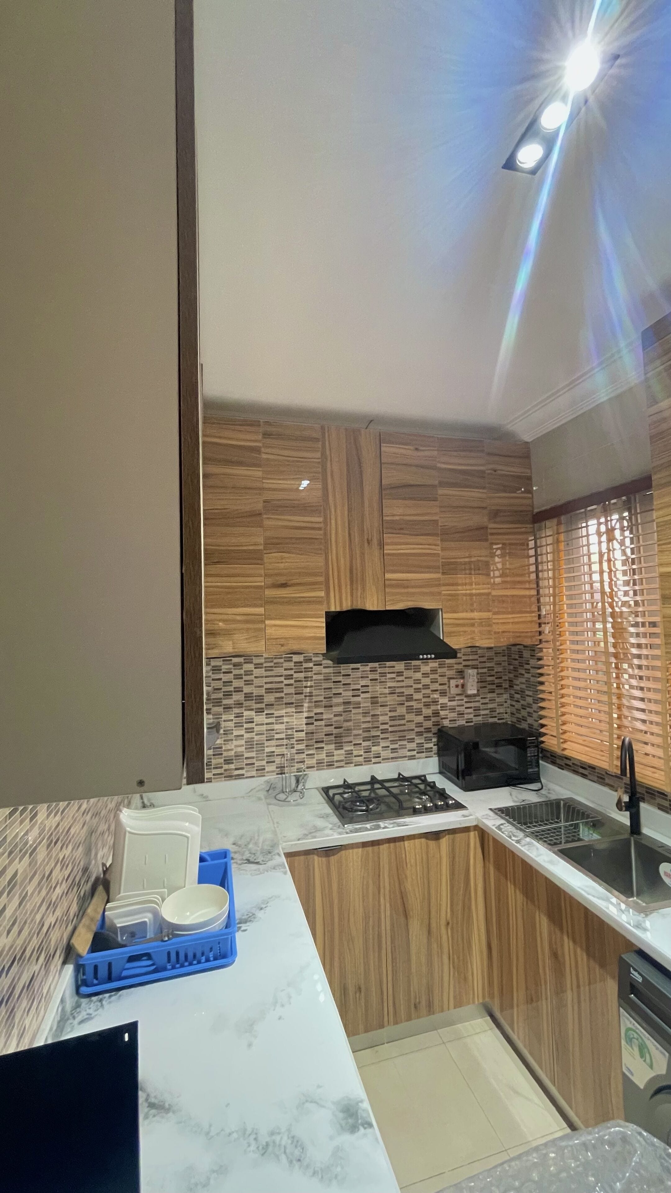 A modern kitchen with wooden cabinets, a gas stove, a microwave, and a sink.