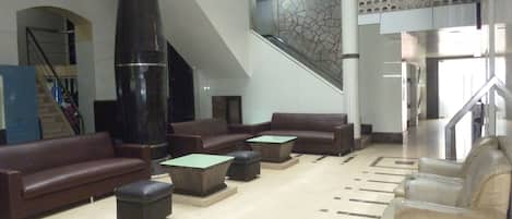 A spacious lobby with a high ceiling, a staircase, and a modern design.