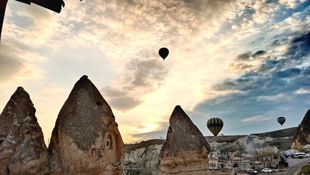 A view of a town with unique rock formations and a hot air balloon in the sky. - Mosaic Cave Hotel (Nevsehir)