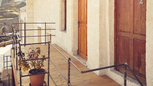 A building with a wooden door, a potted plant, and a metal railing. - Mosaic Cave Hotel (Nevsehir)