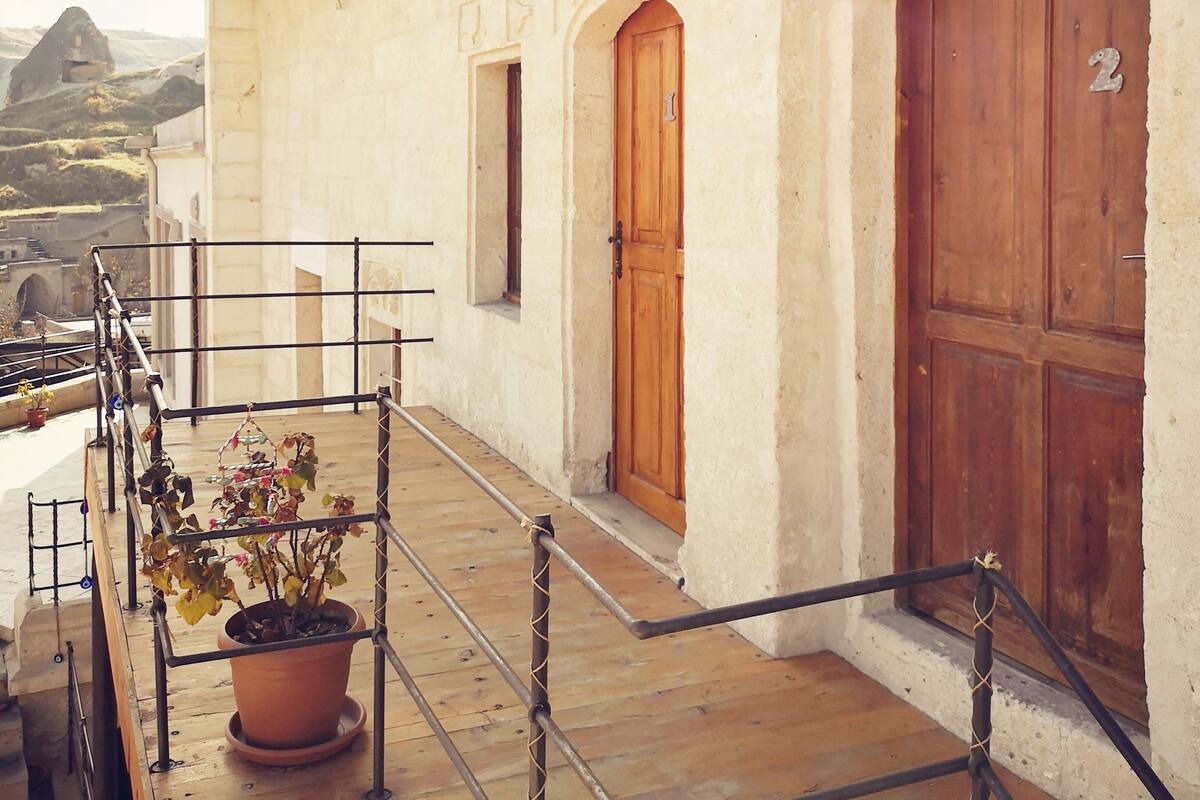 A building with a wooden door, a potted plant, and a metal railing.