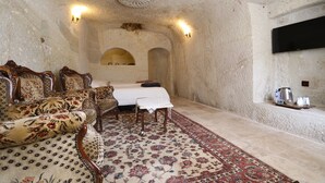 A room with a bed, a sofa, a small table, and a TV mounted on the wall. - Mosaic Cave Hotel (Nevsehir)