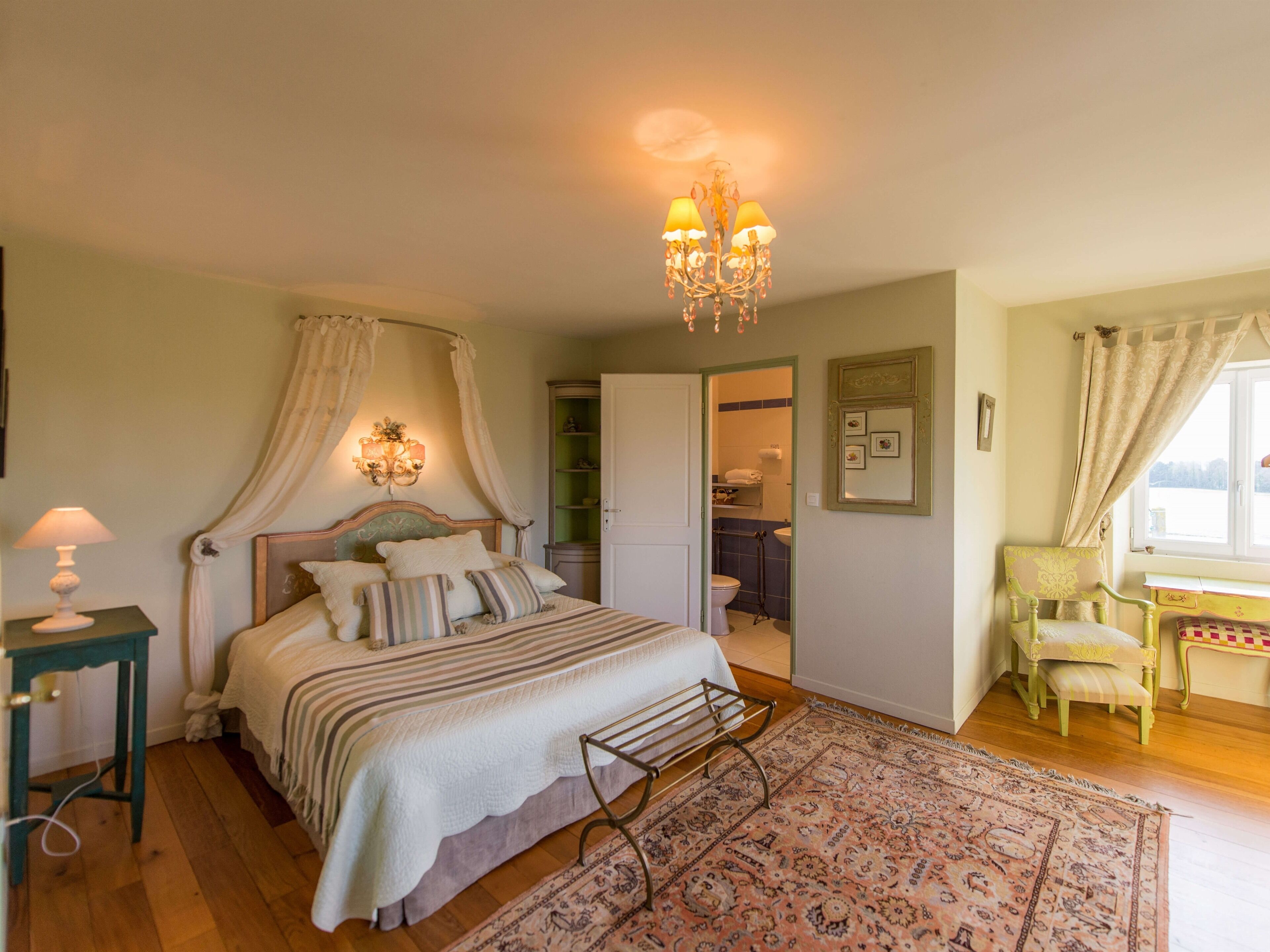 A bedroom with a bed, bedside table, and a chandelier.
