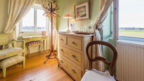 A room with a wooden dresser, a chair, a desk, and a lamp. There is a window with a view of the outdoors. - Chambres D'hotes La Barbinais Bed&breakfast St Malo (Saint-Malo)