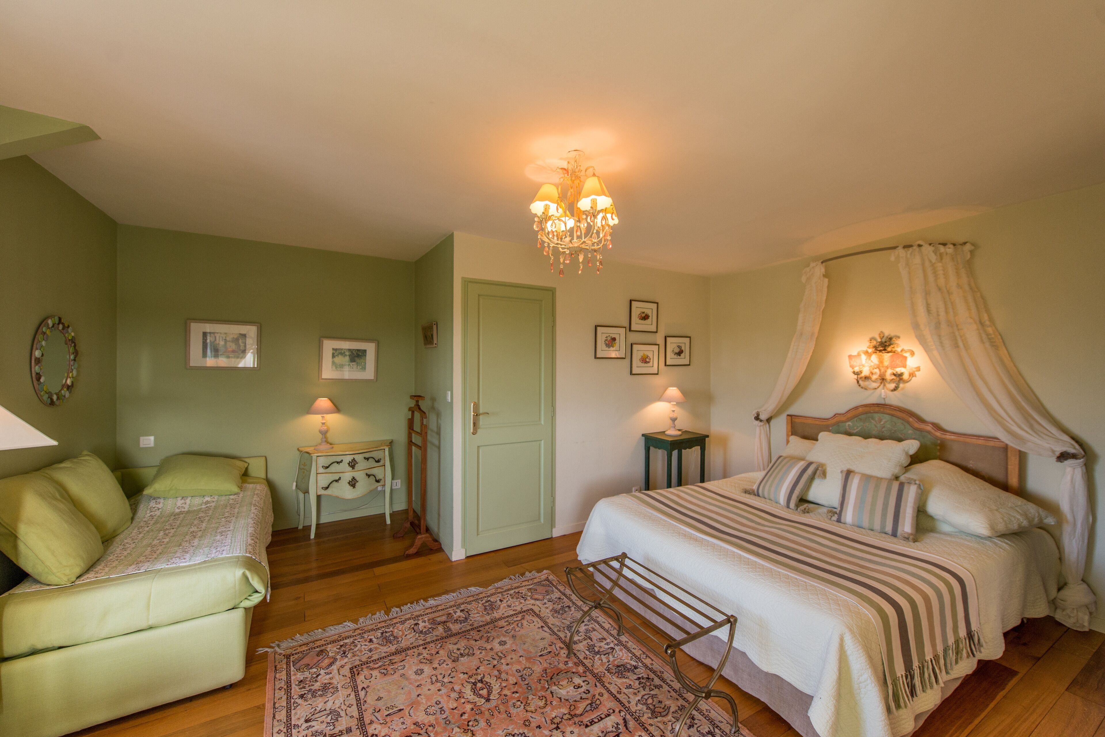 Un dormitorio con una cama, una silla, una mesita de noche, una lámpara y un candelabro.