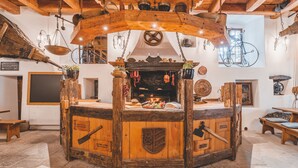A rustic wooden room with a central fireplace, wooden beams, and a bicycle mounted on the wall. - Krumlov Mill Apartments (Cesky Krumlov)