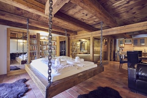 A spacious bedroom with a four-poster bed, a wooden ceiling, and a visible bathroom with a sink and mirror. - Krumlov Mill Apartments (Cesky Krumlov)