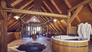 A rustic interior with a wooden hot tub, a cowhide rug, and a kitchen area. - Krumlov Mill Apartments (Cesky Krumlov)