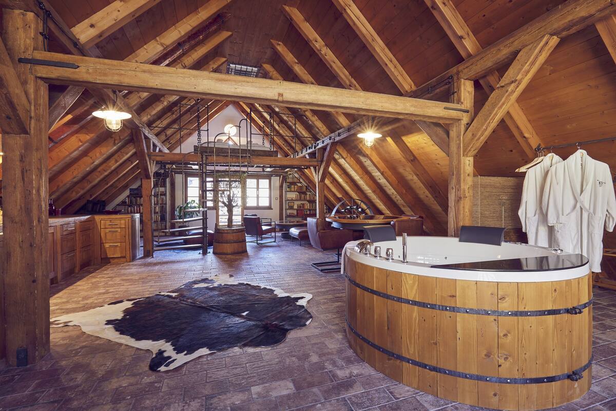 Ein rustikales Interieur mit einer Holztonne, einem Kuhfellteppich und einer Küchenzeile.