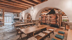 A rustic interior with wooden tables and benches, stone walls, and a stone fireplace. - Krumlov Mill Apartments (Cesky Krumlov)