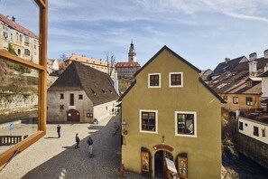 A historic building with a cobblestone street and a river. - Krumlov Mill Apartments (Cesky Krumlov)