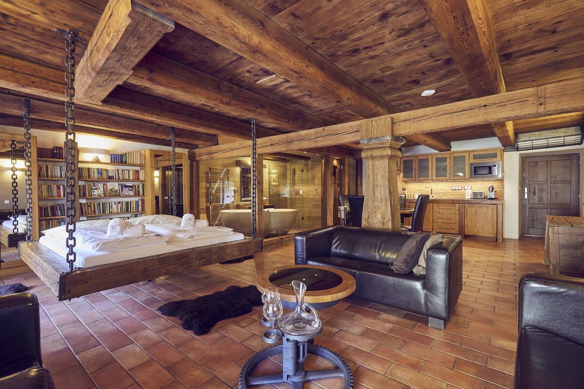 Ein geräumiges Zimmer mit einem großen Bett, einem Ledersofa, einem Couchtisch und einem Bücherregal.