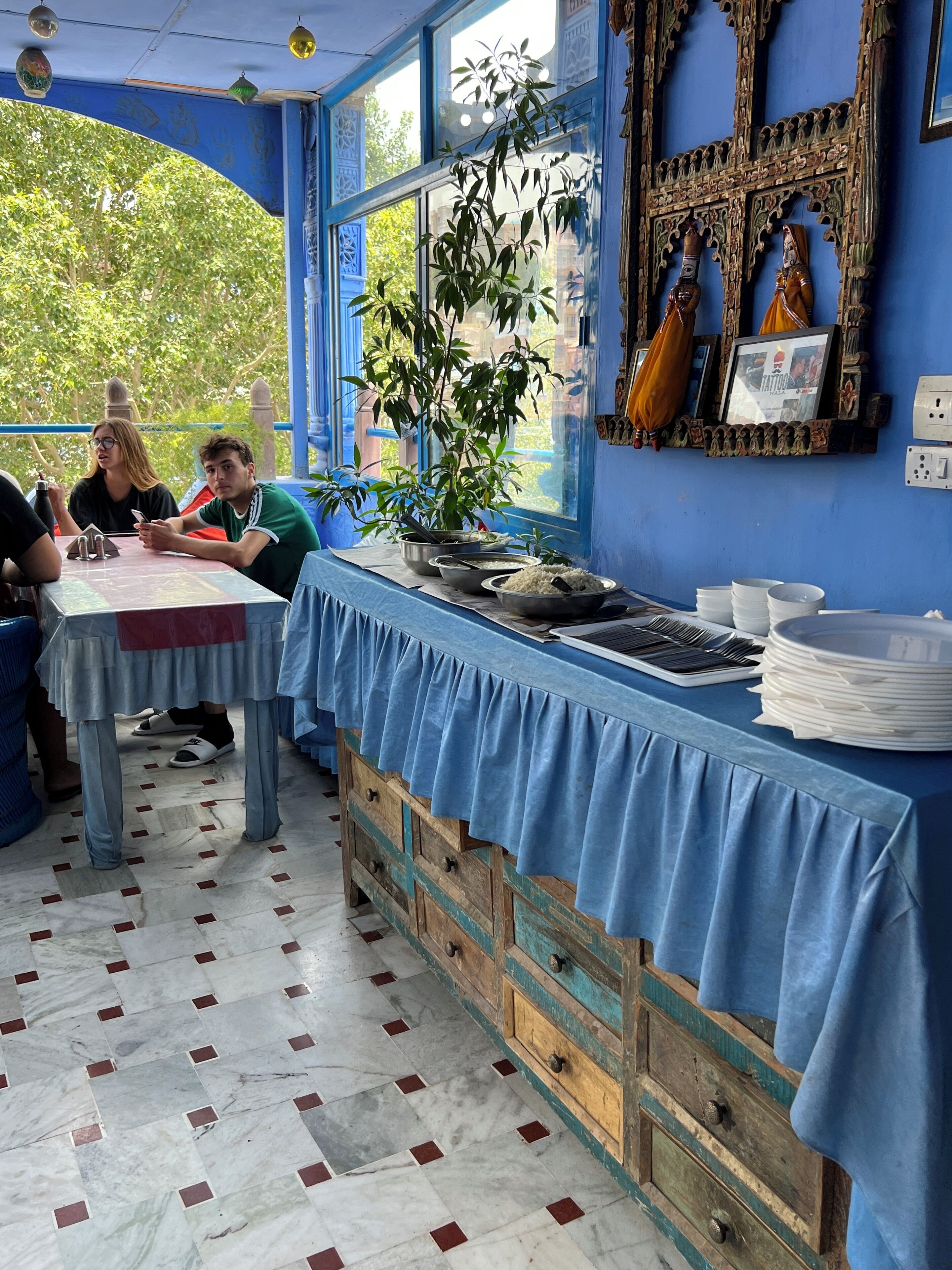 Un restaurant dont l’intérieur est bleu, avec un sol en marbre et un banc en bois.