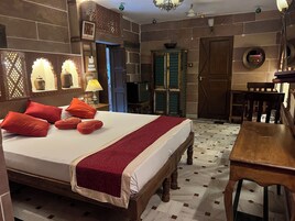 Un dormitorio con una cama grande, un escritorio de madera y una silla.