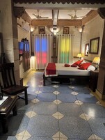 Een slaapkamer met een bed, een stoel, een bureau en een plafondventilator.